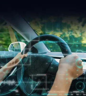 Hands on steering looking out the front window with an electronic overlay on the dashboard.