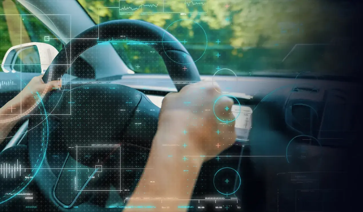 Hands on steering looking out the front window with an electronic overlay on the dashboard.